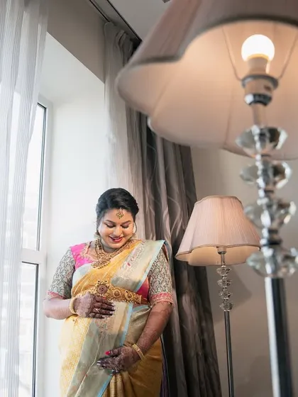 A beautifully composed portrait of an expectant mother by a window, with the frame of a lamp adding depth and warmth to the scene.