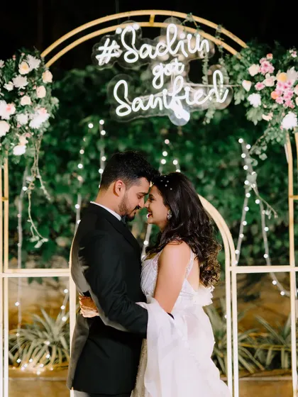 The couple shares an intimate moment under their personalized neon sign. This modern decor element is a popular way to add a personal and trendy touch to any celebration.
