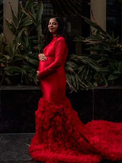 A solo portrait of a client in the red long-sleeved mermaid gown with a ruffled train. The contrast of the sleek body and the voluminous train creates a very dynamic and interesting silhouette.