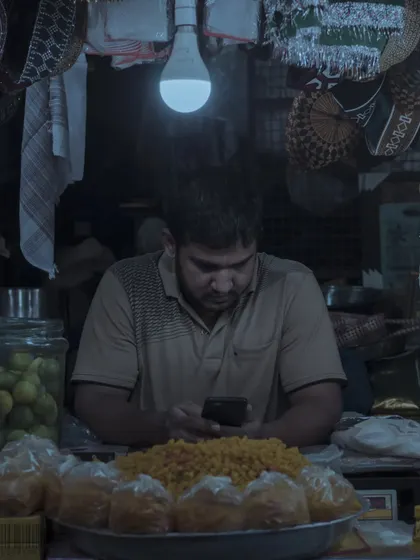 A shopkeeper engrossed in his phone under the single light of his stall. This is a common sight in modern India, and I love capturing these moody, contemporary moments.