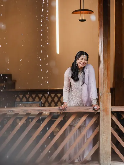 The bride's genuine laughter is captured perfectly in this shot, as she stands on a balcony with a sprinkle of rain or petals around her.