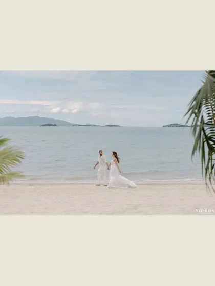 A wide, cinematic shot of the couple walking along a deserted beach, emphasizing the feeling of having the world to themselves.