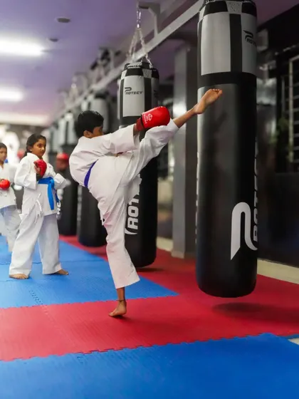 A young blue belt practices a powerful kick on the heavy bag, building strength and technique with every session.