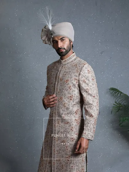 A closer look at the coffee beige sherwani, highlighting the three-dimensional floral artistry and threads that carry culture. This is a garment of grace and grandeur.