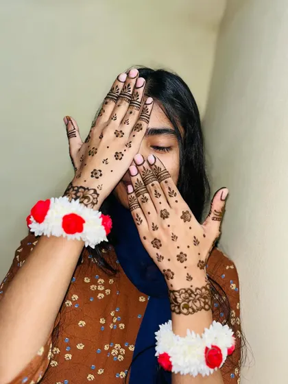 A playful shot of a simple Eid mehndi design. The floral bracelets (gajras) add a festive touch.
