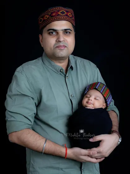 A touch of Himachali tradition. This father is celebrating his heritage by sharing this moment with his newborn.