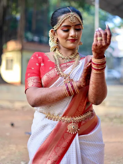 A candid moment of the bride admiring her henna-adorned hands. Her traditional white and red saree and gold jewelry complete this beautiful South Indian bridal look.