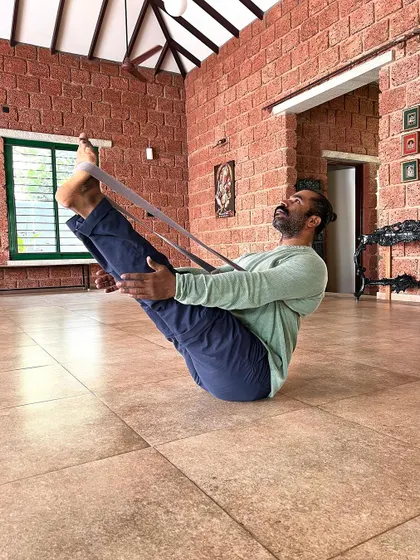 Our "Yoga with Props" classes use tools like straps to support you physically and mentally. Here, a strap assists in Navasana (Boat Pose), helping to build core strength with proper alignment.