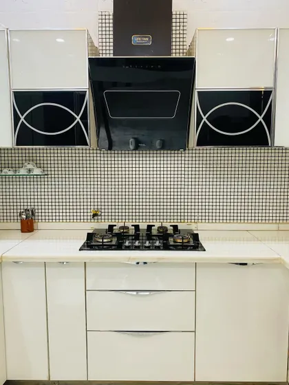 A symmetrical view of the cooking area, with a modern chimney flanked by upper cabinets featuring a unique black and white graphic design.