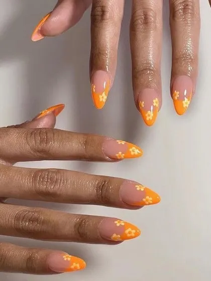 Bright orange tips get a cute upgrade with a subtle, hand-painted daisy pattern. This design combines the popular colorful tip trend with a touch of delicate floral nail art.