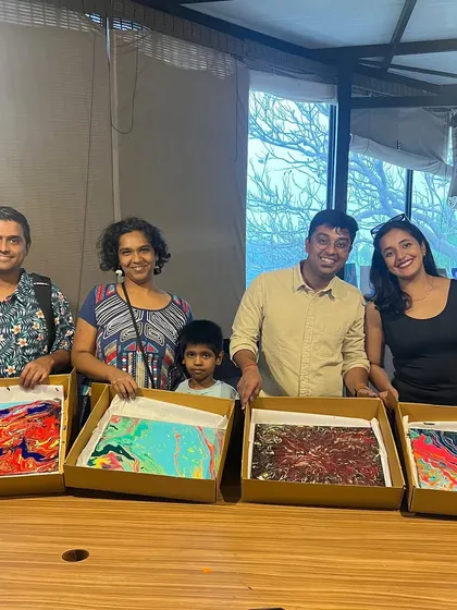 A happy group showing off their finished fluid art pieces. The vibrant colors and abstract patterns make for some seriously cool art.