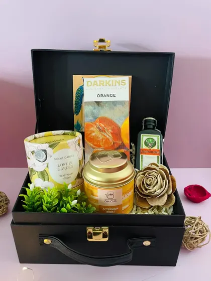 This curation combines a scented candle, tea, and a miniature liquor bottle, offering a relaxing and indulgent gift set for the festive season.