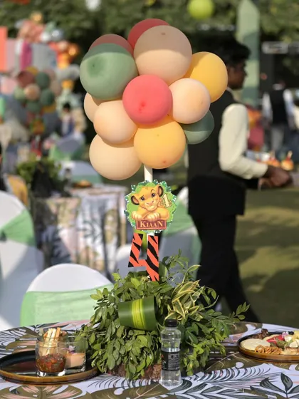 A themed table centerpiece for the Lion King party, with a small balloon cluster and a cutout of Simba.