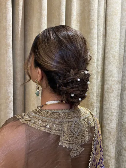 Another view of the textured low bun with pearls. The indoor lighting highlights the shine and dimension of the hair, showing how the style looks in a different setting.