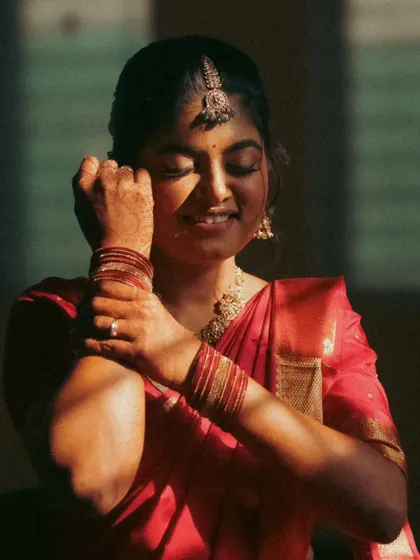 A bride enjoying a quiet moment in the sun. The light creates beautiful shadows on her face as she adjusts her bangles, a simple, elegant, and candid shot.