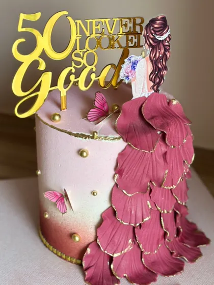 Celebrating a milestone like 50 deserves a cake that’s as fabulous as the person it's for. This design features an elegant flowing gown made of delicate, hand-shaped petals, blush tones, and gold accents, proving that 50 never looked so good.