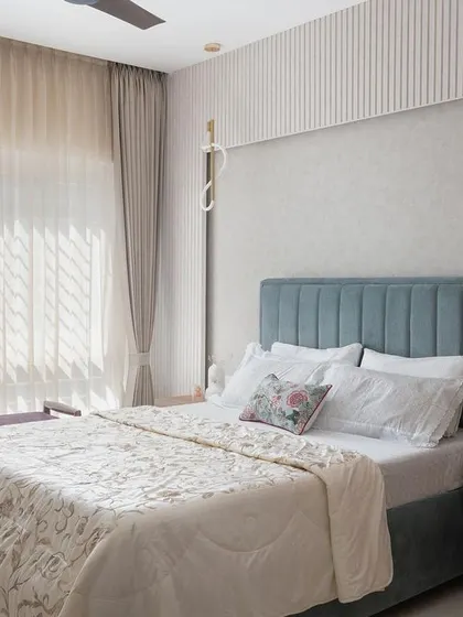 This bedroom uses a softer, pastel blue palette for the headboard, complemented by light wood tones and ample natural light to create a serene and airy retreat.