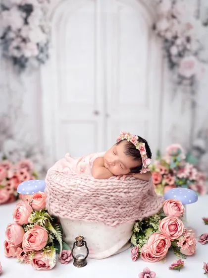A dreamy floral scene for a sleeping baby. Nestled in a soft pink knit, this little one is surrounded by a garden of beautiful pink flowers.