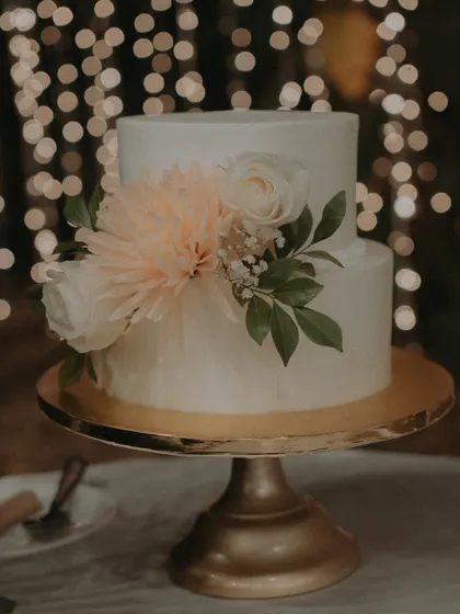 A beautiful shot of the simple and elegant two-tiered engagement cake, adorned with fresh flowers.