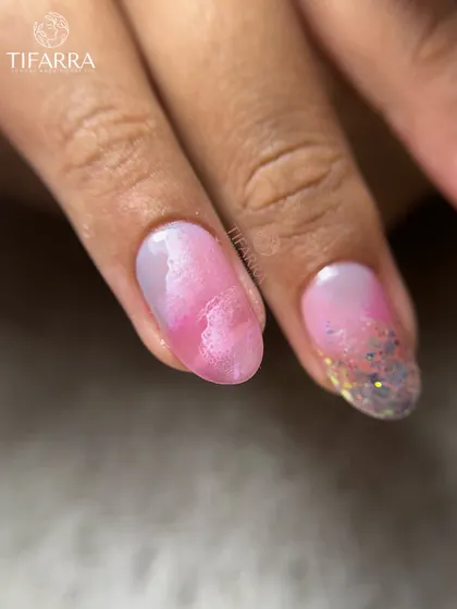Cotton-candy dreams with a touch of sparkle. A close-up of a nail with a pink watercolor effect and a glittery tip.