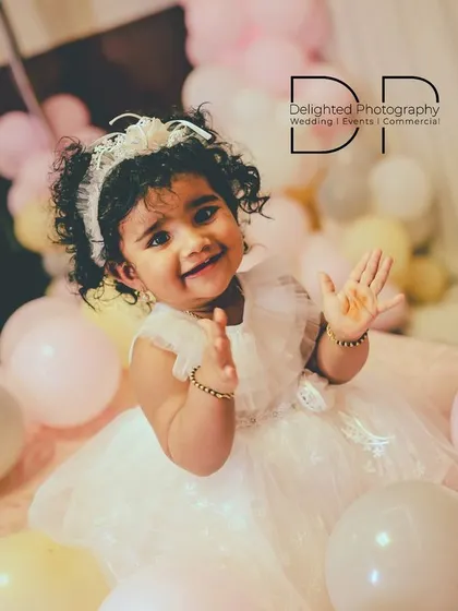 A joyful photo of the one-year-old birthday girl smiling and clapping, perfectly capturing the happiness of her special day.