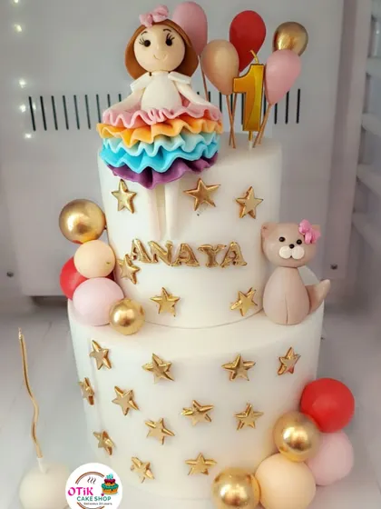 A first birthday is a magical milestone. We created this two-tiered cake with a rainbow-dressed doll, a cute teddy bear, and shimmering gold stars to make the celebration extra special.