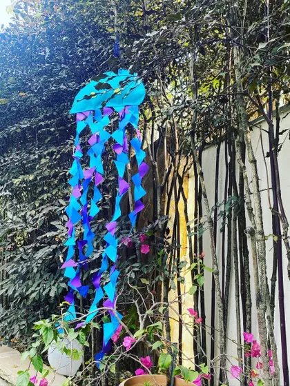 A handmade jellyfish decoration hangs from a tree, its colorful paper tentacles dancing in the breeze. I use the natural environment of a backyard to hang decorations and enhance the theme.