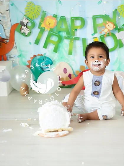 Getting right into the fun. This shot captures the tactile joy of a baby digging into his first birthday cake, surrounded by a playful jungle animal theme.