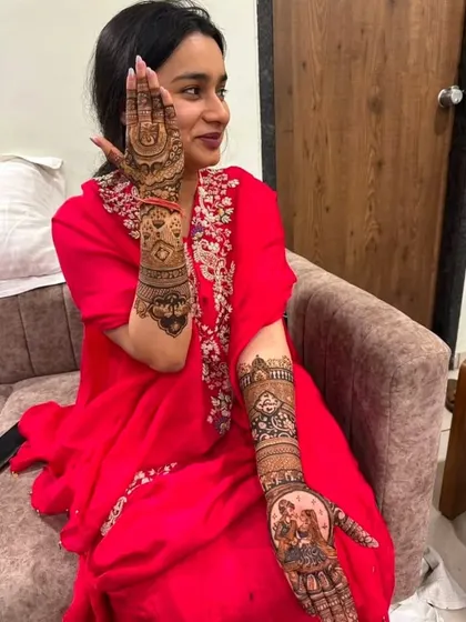 A candid shot of a client showing off her beautiful portrait mehndi, which tells a story on her hands and arms.