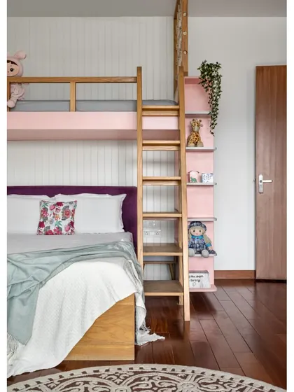 The bunk bed in the 'Vasudhalayah' daughter's room maximizes floor space for play. The integrated ladder and bookshelf make the design both fun and highly functional.