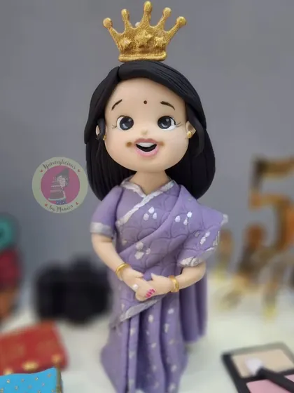 A close-up of the elegant 50th birthday figurine, wearing a crown and a beautiful purple saree.