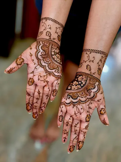 A close-up of the reception mehendi, showing the combination of a bold wrist cuff and delicate floral vines.
