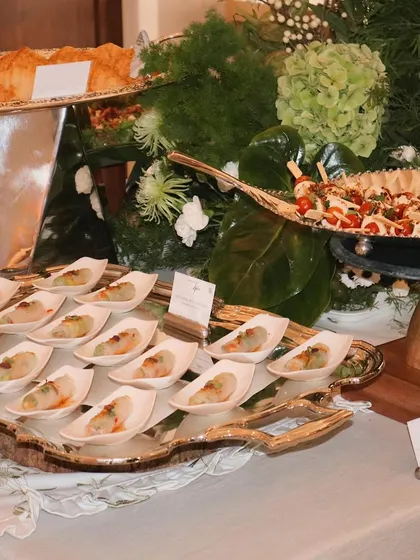 A wide shot of one of our elegant green and white themed grazing tables, showcasing the variety of appetizers and the beautiful floral arrangements.