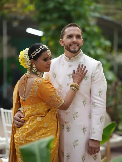 A beautiful portrait of the couple after their ceremony. The bride is wearing a traditional yellow silk saree, and the groom is in a custom-embroidered sherwani, perfectly complementing the lush, natural setting of their intimate wedding.