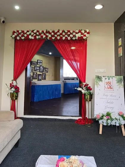 The entrance to a baby shower event, decorated with red drapes and floral arrangements.