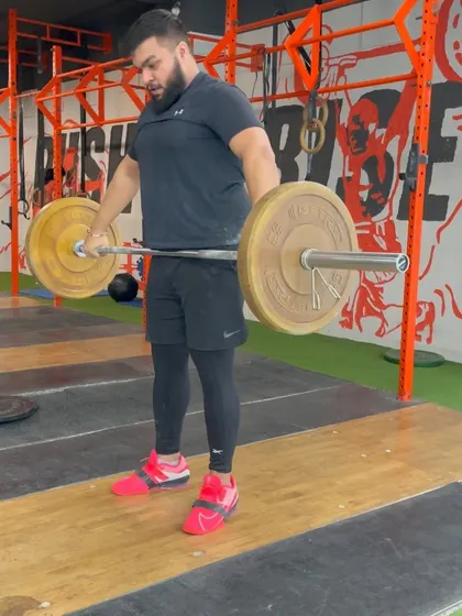 A lifter at the start of a hang snatch. The focus here is on maintaining tension in the hamstrings and back before initiating the explosive second pull.