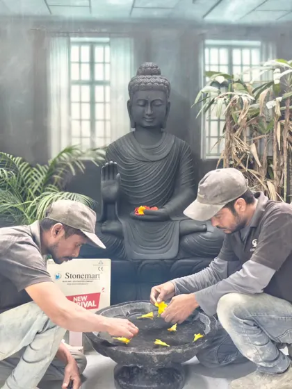 My team carefully places flowers in the uruli bowl in front of the large garden Buddha statue, preparing it for a photoshoot. This shows how the piece can be styled.