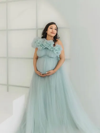 A serene portrait in a minimalist studio setting. The soft ice blue color and flowing tulle of the gown create a peaceful and elegant atmosphere.