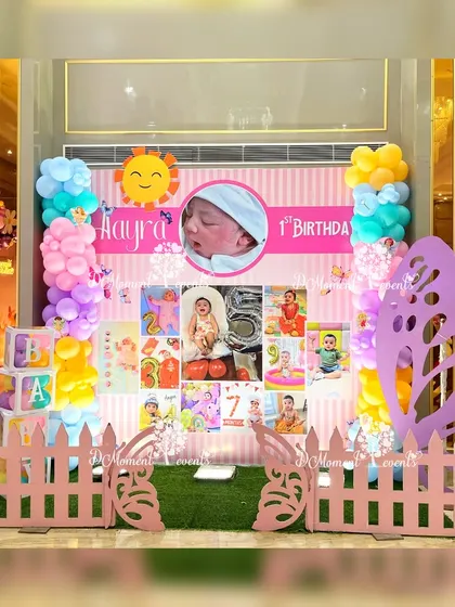 A colorful first birthday milestone board with a picket fence and butterfly prop, perfectly matching the vibrant fairy and butterfly theme.