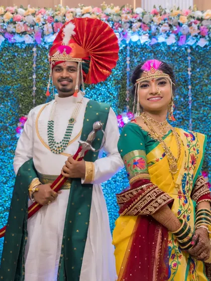 A classic full-length portrait of the couple against a floral backdrop, showcasing their magnificent wedding outfits.