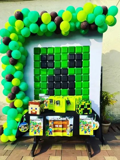 A creative Minecraft-themed party setup. We built a Creeper face backdrop using green and black elements and included game-themed gift bags and props to bring the popular video game to life.