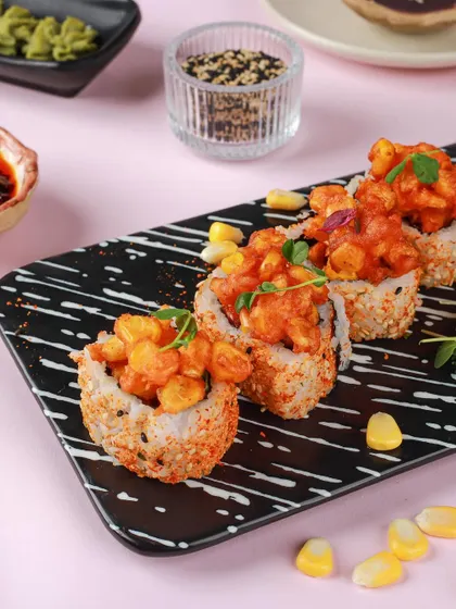 Spicy corn sushi rolls presented on a modern black and white striped plate, looking fresh and contemporary.