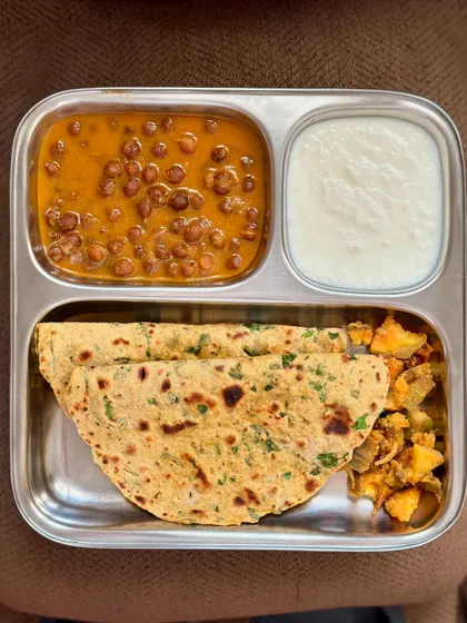 A hearty meal of methi paratha, black chickpea curry, sautéed potato, and curd.