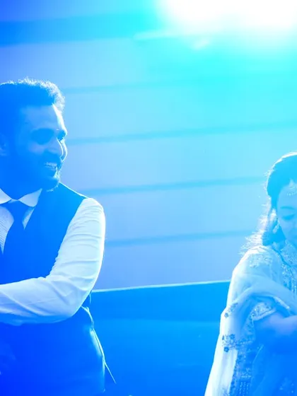 A candid shot of a couple dancing under blue stage lights at their sangeet or reception.