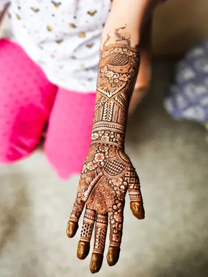 A single arm shot highlighting the majestic peacock motif at the top of the design.