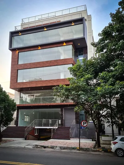 A completed commercial building featuring a facade with a mix of wood-textured panels and extensive glass, creating a warm yet modern aesthetic.
