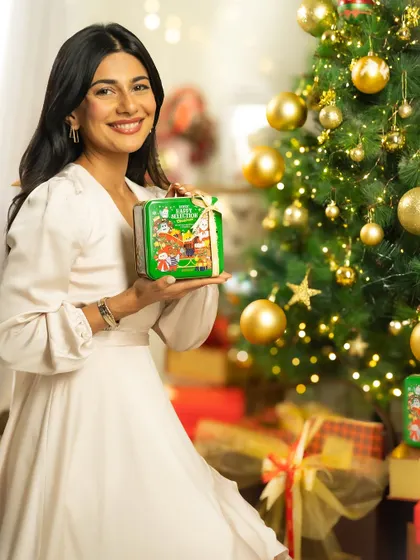 A full-length shot of a model with a Christmas gift, showcasing the product in a festive home environment.