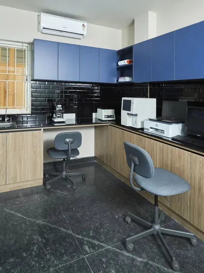 The clinic's laboratory is streamlined and modern. The contrast of blue cabinetry against black subway tiles and wood-look cabinets creates a space that is both bold and professional.