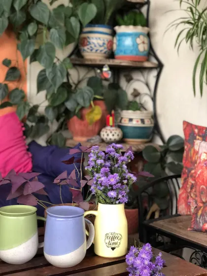 A cozy corner perfect for coffee time, decorated with fresh-cut purple asters. Flowers have a way of brightening any space and symbolizing new beginnings.