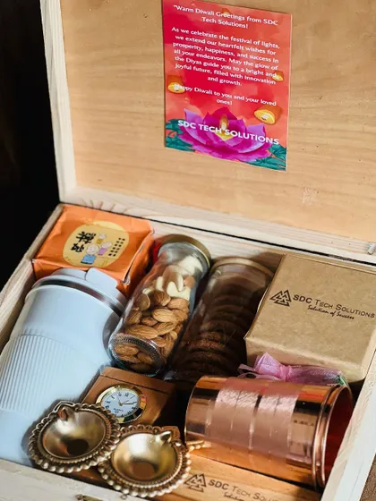 An inside look at a corporate Diwali hamper, containing a travel mug, a jar of almonds, cookies, and other branded items for 'SDC Tech Solutions'.